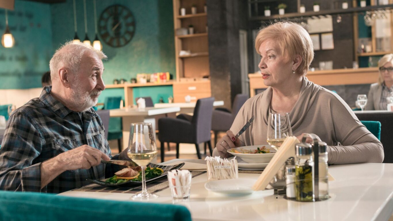 Elegant dining experience with couple enjoying gourmet meal and wine in stylish hotel restaurant.