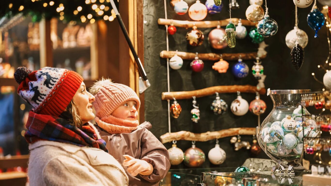 Guests at Christmas market enjoying festive decorations and warm atmosphere, ideal for holiday stays with family.